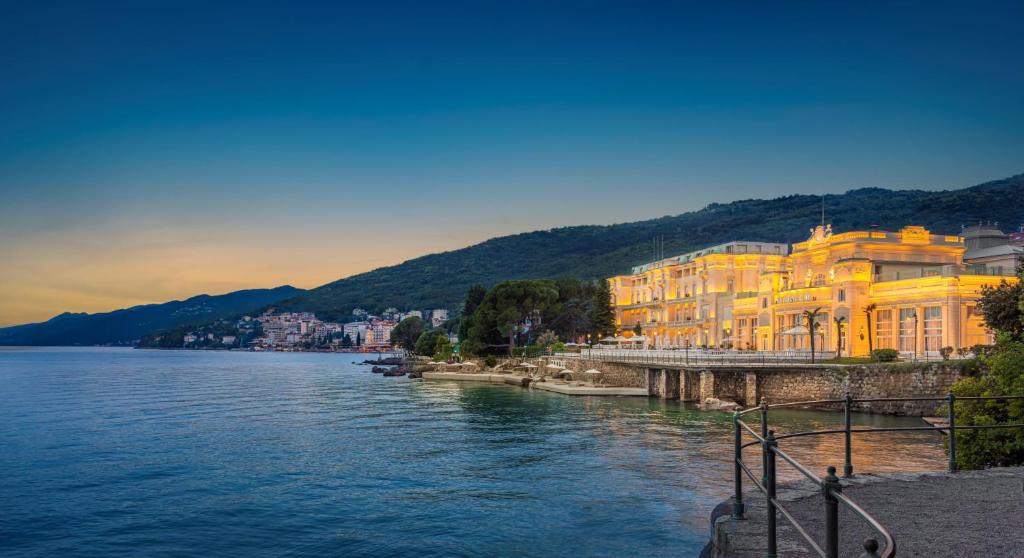 a large yellow building next to a body of water at Hotel Kvarner - Liburnia in Opatija