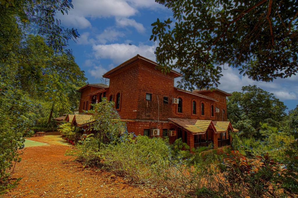 um velho edifício de tijolos vermelhos no meio de um campo em Konkan Nest Resort em Ganpatipule