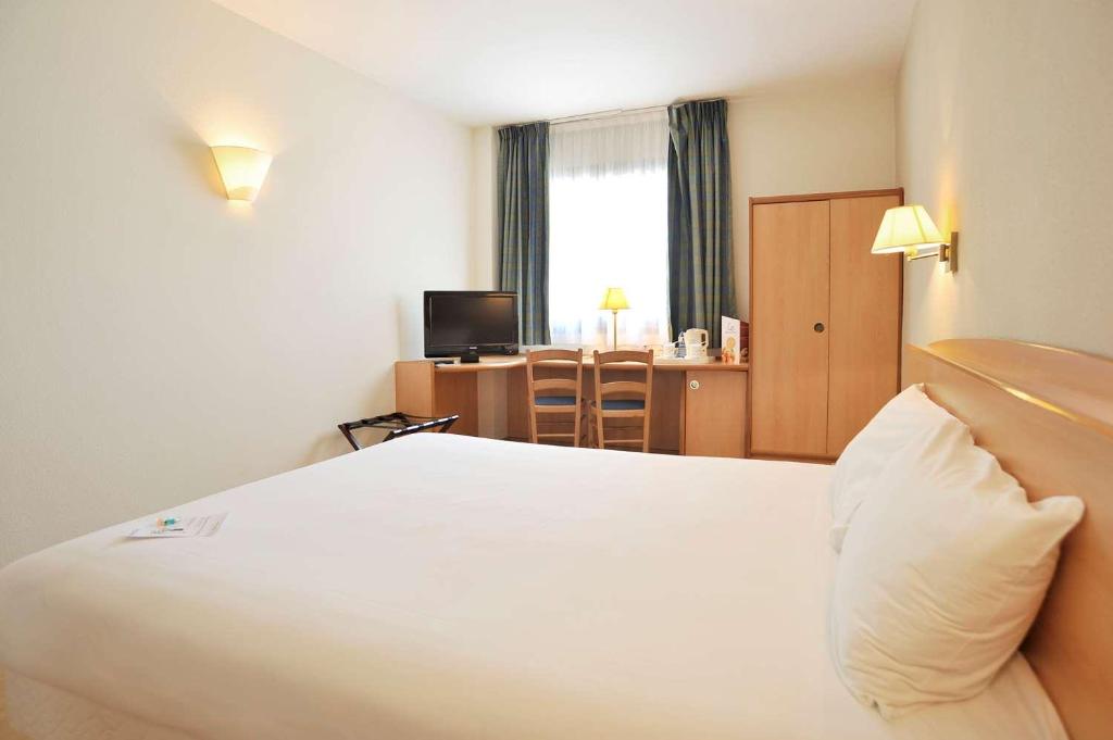 Habitación de hotel con cama blanca y escritorio en Travelodge Murcia, en Murcia