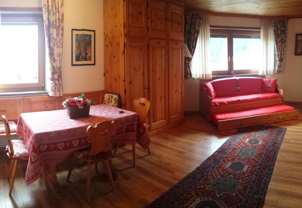 a living room with a table and a red couch at Supermountainski Colfosco in Colfosco