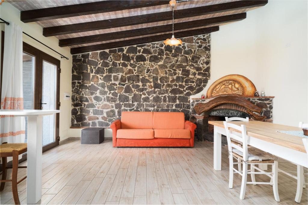 salon z pomarańczową kanapą i kamienną ścianą w obiekcie Casa Sole w mieście Dorgali