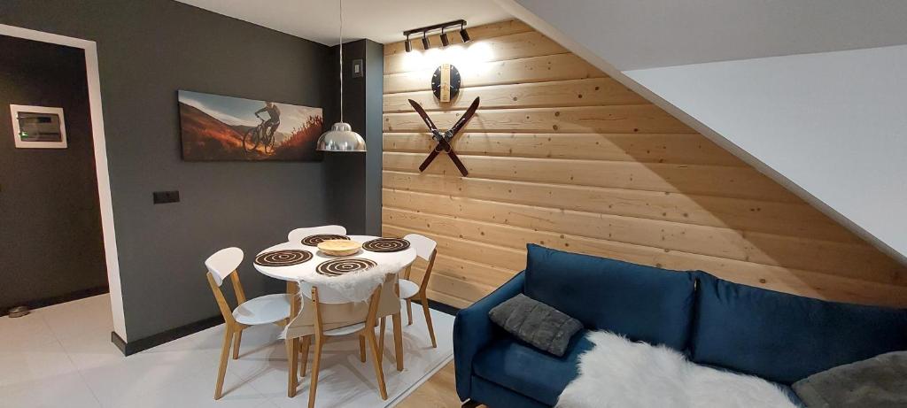 a living room with a table and a blue couch at Apartamenty Trzy Kopce SKI & BIKE & SAUNA in Ustroń