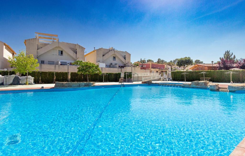 a large blue swimming pool with buildings in the background at 2 Bedroom Beautiful Home In Castalla in Castalla