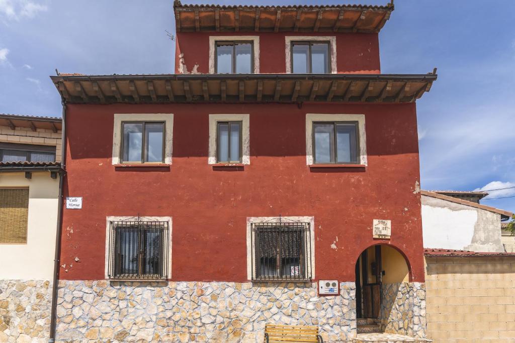Un edificio rojo con ventanas enrejadas en un muro de piedra. en La Pedraja de Atapuerca, en Galarde