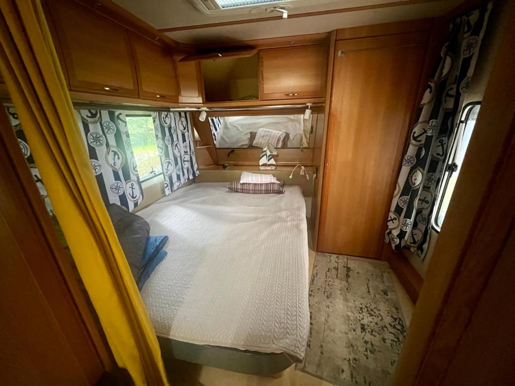 a small room with a bed in an rv at Dębki przyczepa kempingowa Fendt in Dębki