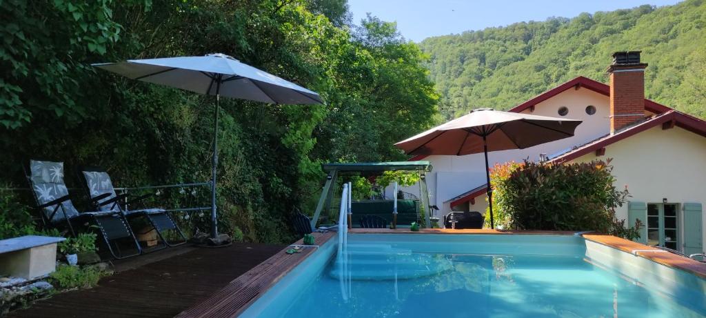 a swimming pool with an umbrella and a house at Mon Plaisir in Villefranche-de-Rouergue