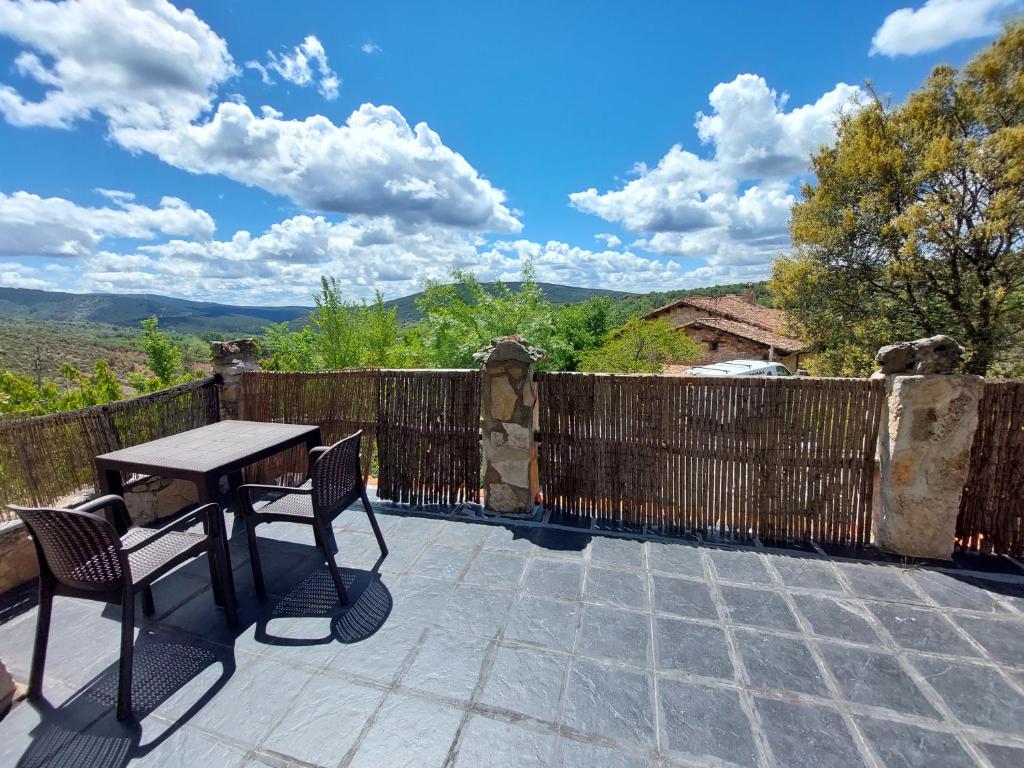 un patio con una valla de madera, una mesa y sillas en Las Peonías Casa Rural en Almiruete