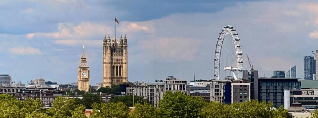 una città con una torre dell'orologio e l'occhio di Londra di River Panorama Central London 2 bedroom New Development a Londra