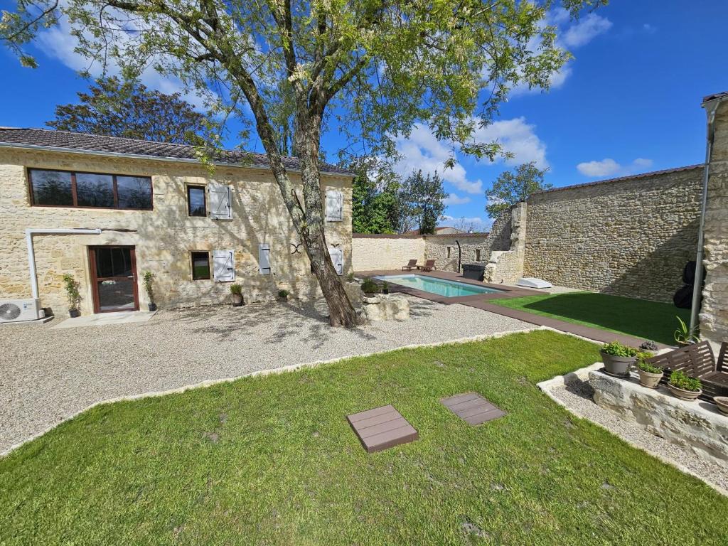 une maison en pierre avec un arbre et une piscine dans l'établissement Enfin libre, à Jau-Dignac-et-Loirac