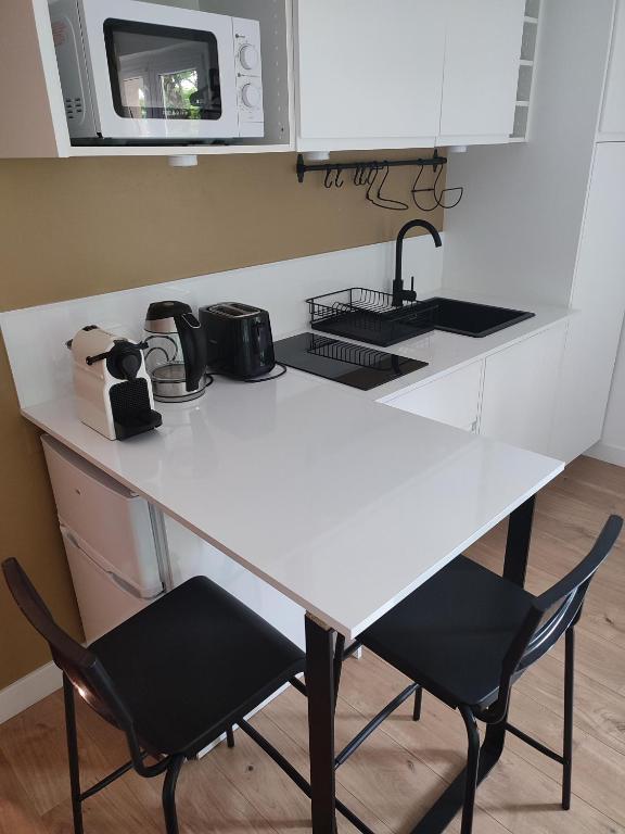 une cuisine avec une table blanche et deux chaises dans l'établissement Studio Vannes - centre-ville et parking, à Vannes