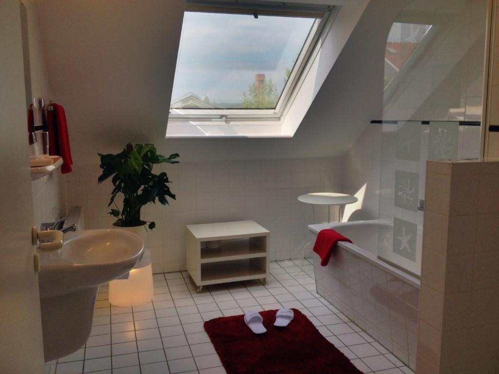 a bathroom with a sink and a tub and a window at Apartmenthaus Feuerbach in Leipzig