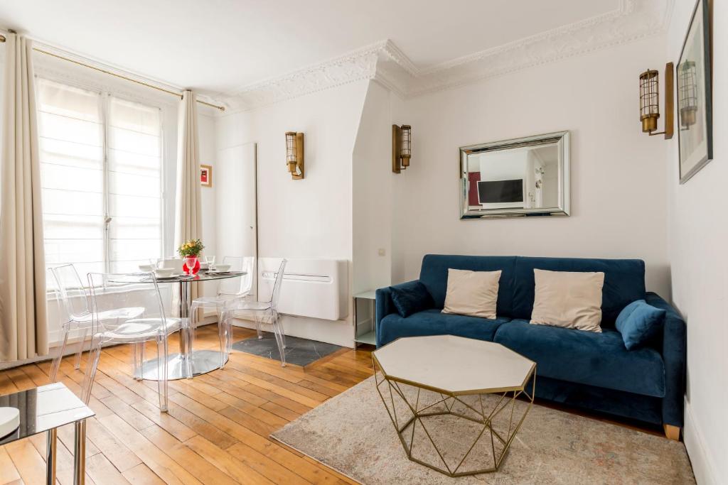 un salon avec un canapé bleu et une table dans l'établissement Saint Paul le Marais Charlemagne, à Paris