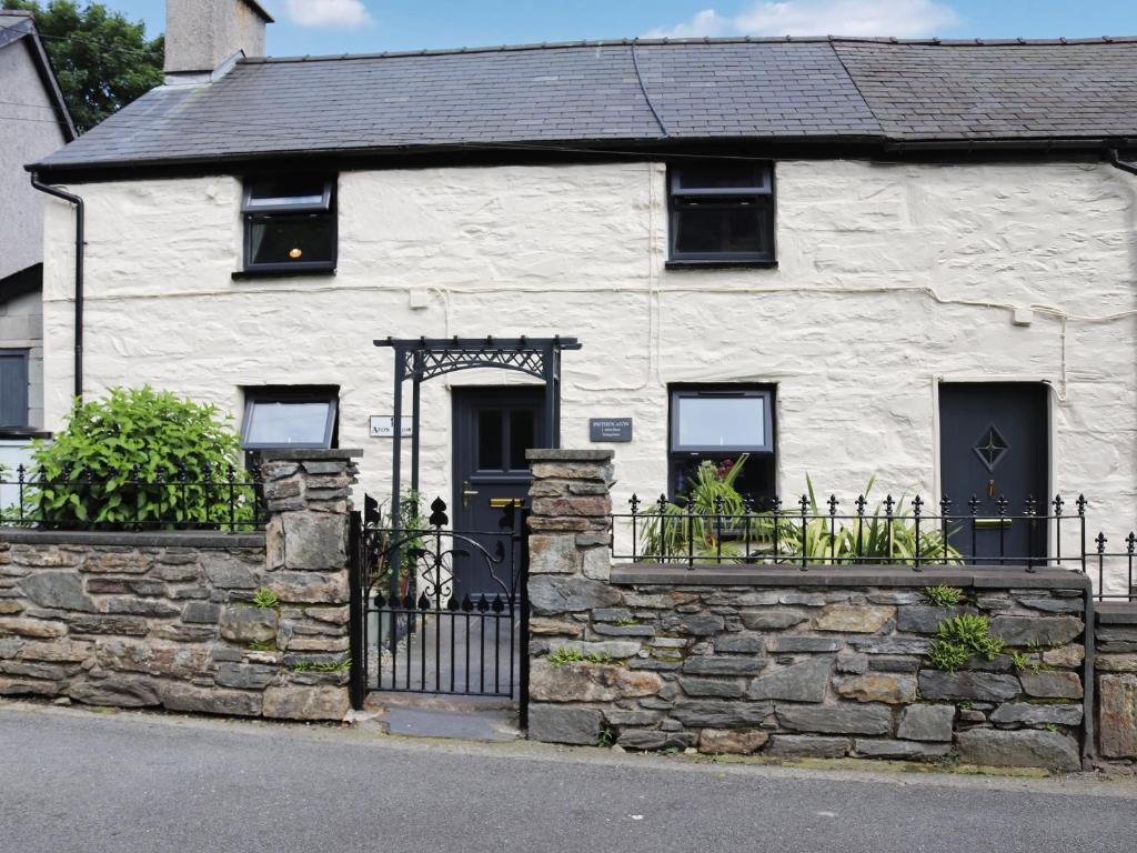 een wit stenen huis met een zwarte poort bij Bwthyn Afon in Blaenau-Ffestiniog