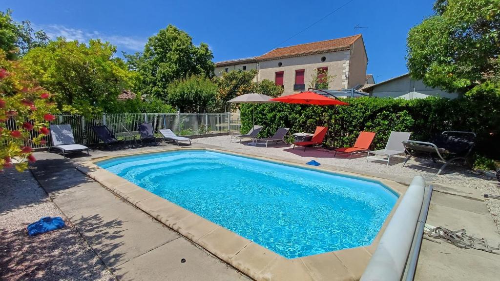 a swimming pool in a yard with chairs and umbrellas at Canta aoussel in Moussoulens