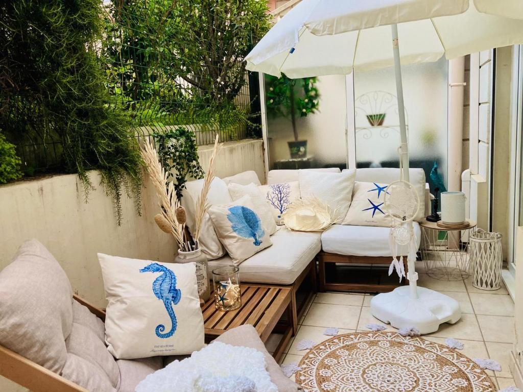 un patio avec des canapés et un parasol sur un patio dans l'établissement **2P Calme Climatisé, Terrasse, Centre Menton, Proche Plages et Commerces** - FR-1-196-356, à Menton