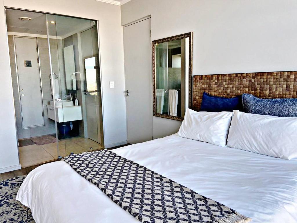 1 dormitorio con 1 cama blanca grande y baño en Luxury Masingita towers 9th floor apartment, en Johannesburgo