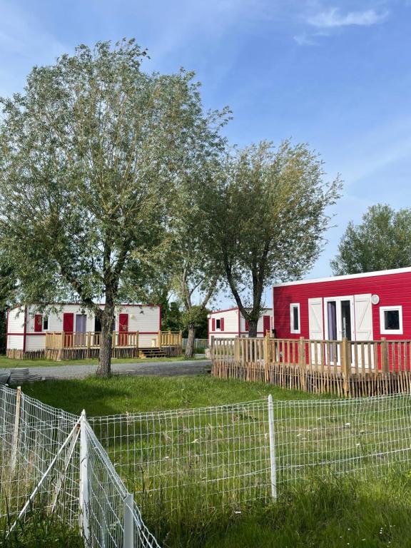 une maison rouge et blanche avec des arbres et une clôture dans l'établissement Le Clos des Soulacaises, à Soulac-sur-Mer