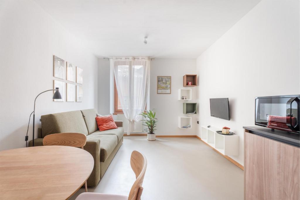 a white living room with a couch and a table at Casa Clara, old town experience in Riva del Garda
