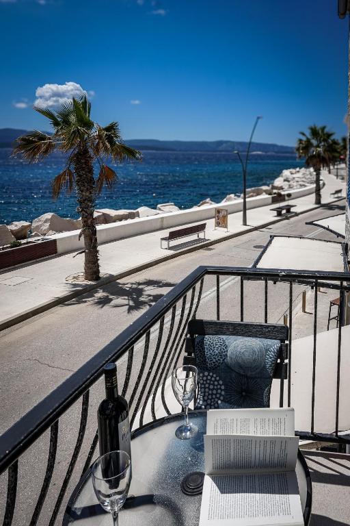 a table with wine bottles and glasses on a balcony at Seaside Apartments Bol in Bol