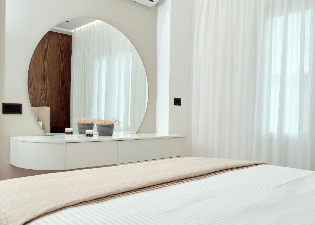een witte slaapkamer met een spiegel en een bed bij Goodija Central Tirana 2 in Tirana