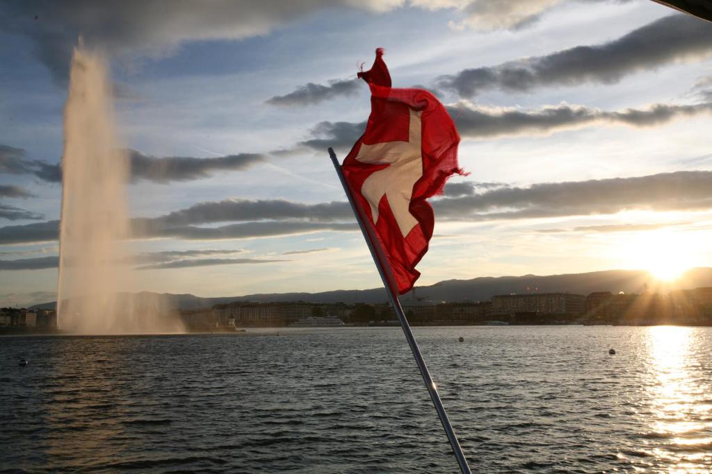 a flag on a boat in the water with a fountain at Floatinn Boat-BnB in Geneva