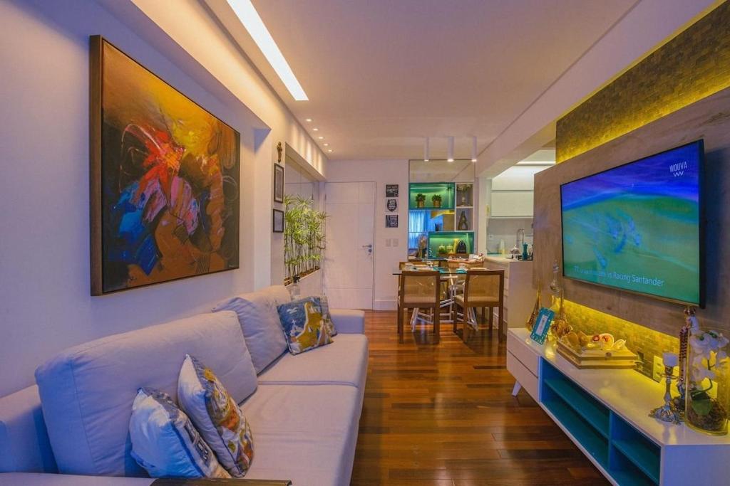 salon z białą kanapą i dużym telewizorem w obiekcie Conforto e Design a Poucos Passos da Praia w mieście Tambaú