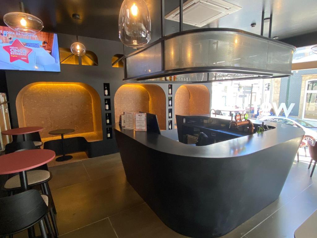 a restaurant with a bar with stools and tables at WOT Porto in Porto