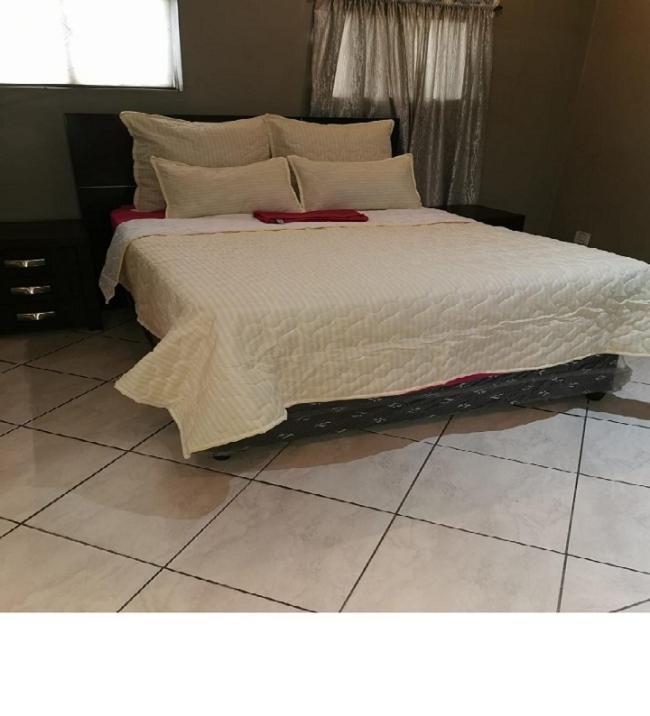 a bedroom with a large bed with white sheets at Ebony Guest House in Pretoria