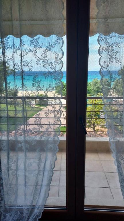 a view of the ocean from a window with curtains at Villa Anna III in Nea Moudania