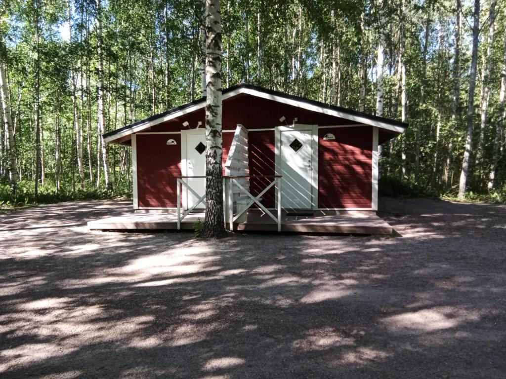a red shed in the middle of a forest at Mäentaustan aitat in Janakkala