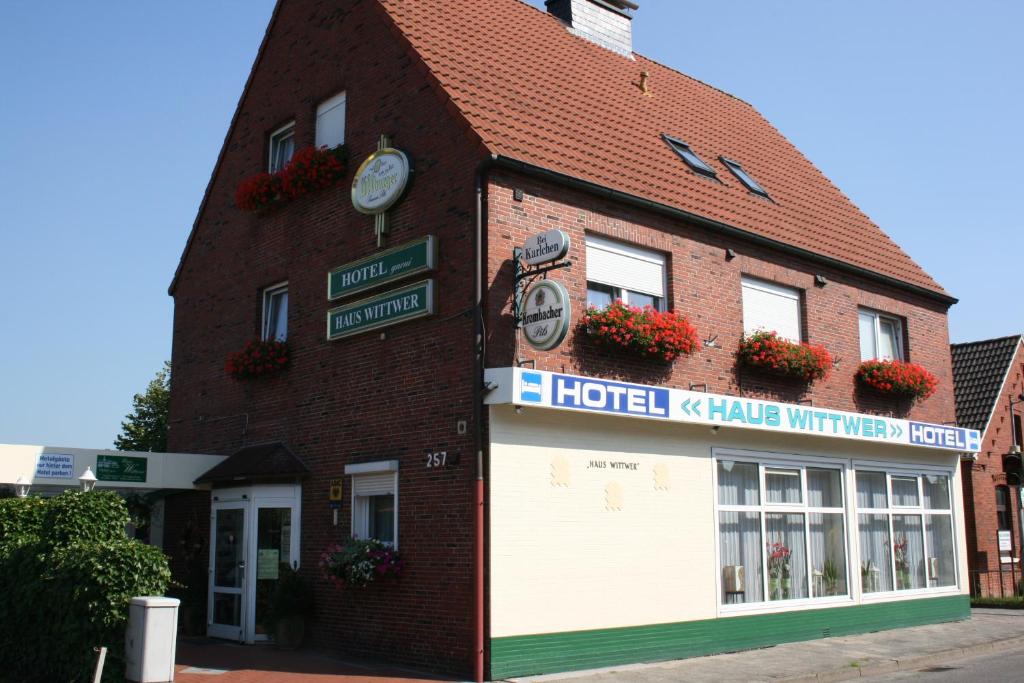 ein Hotelgebäude mit seitlicher Uhr in der Unterkunft Hotel Haus Wittwer in Emden