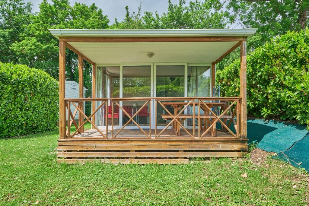 une petite maison avec un porche grillagé sur l'herbe dans l'établissement Mobil Home 4 personnes 208, à Mens