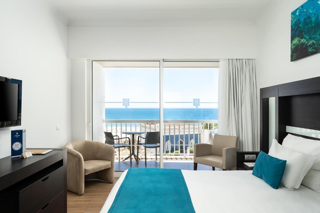 a hotel room with a bed and a view of the ocean at Jupiter Algarve Hotel in Portimão