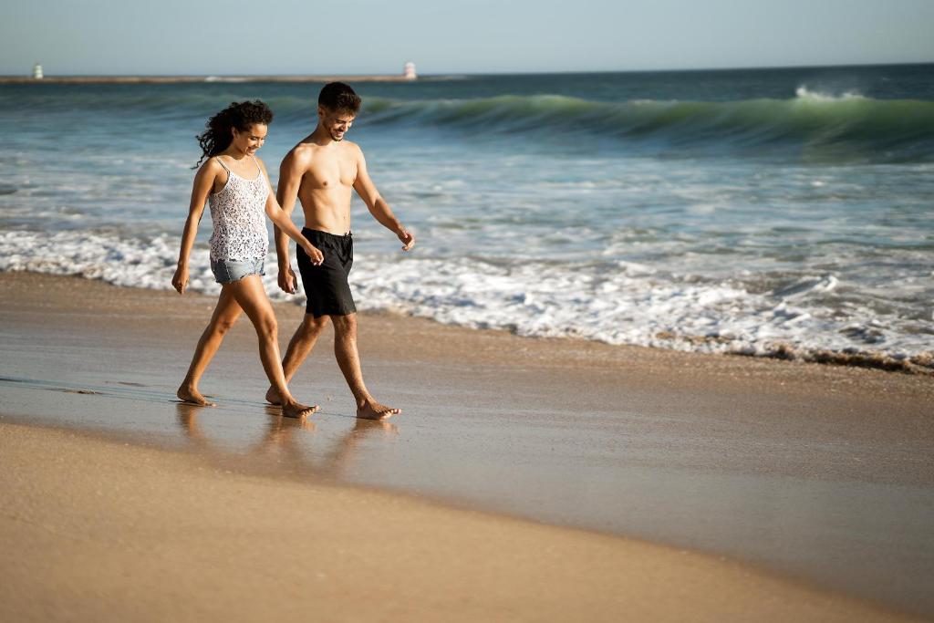a man and a woman walking on the beach at Jupiter Algarve Hotel in Portimão