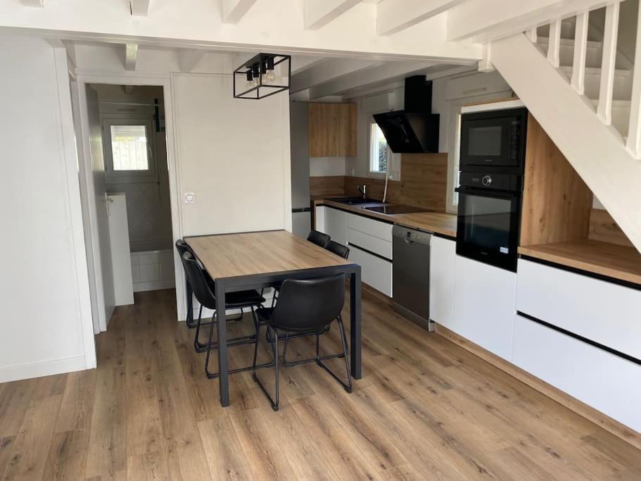Una cocina con una mesa y sillas en una habitación. en Chalet familial La Hume, en Gujan-Mestras