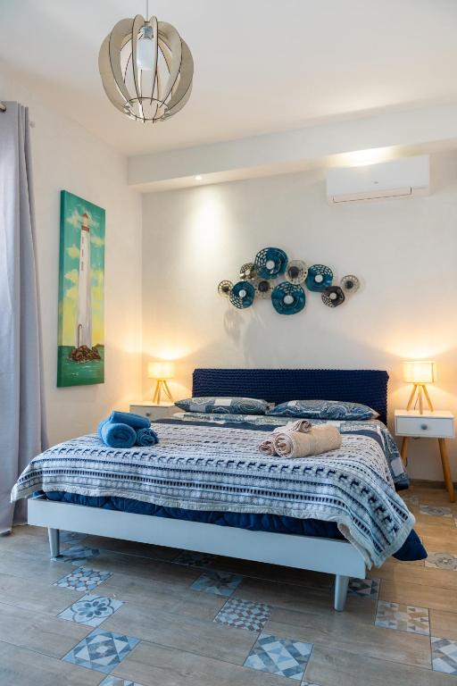 sypialnia z łóżkiem z niebieskimi kocami i żyrandolem w obiekcie Seasons Home San Foca w mieście San Foca