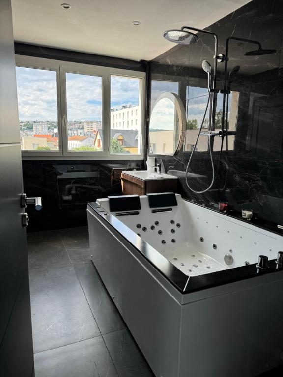 eine große Badewanne im Bad mit Fenstern in der Unterkunft appartement jacuzzi in Le Havre