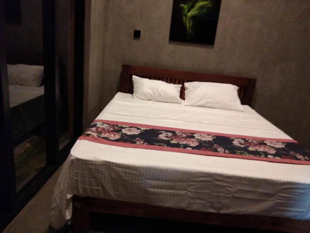 Negombo Morawala Beach Villa في نيجومبو: غرفة نوم مع سرير مع بطانية زهرة عليه