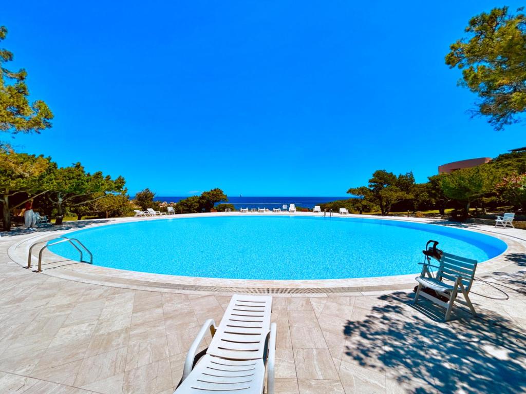 a large swimming pool with two white benches around it at Vistamare Cala Granu in Porto Cervo