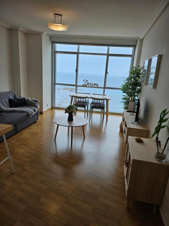 uma sala de estar com um sofá e uma mesa em APARTAMENTO CON INCREIBLES VISTAS A LA PLAYA DE RIAZOR em La Coruña