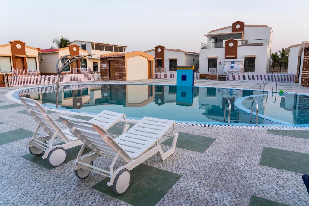a swimming pool with two lounge chairs in front of a house at Flamingo Club and Resort Una 3 Km Away from Diu Check Post in Diu