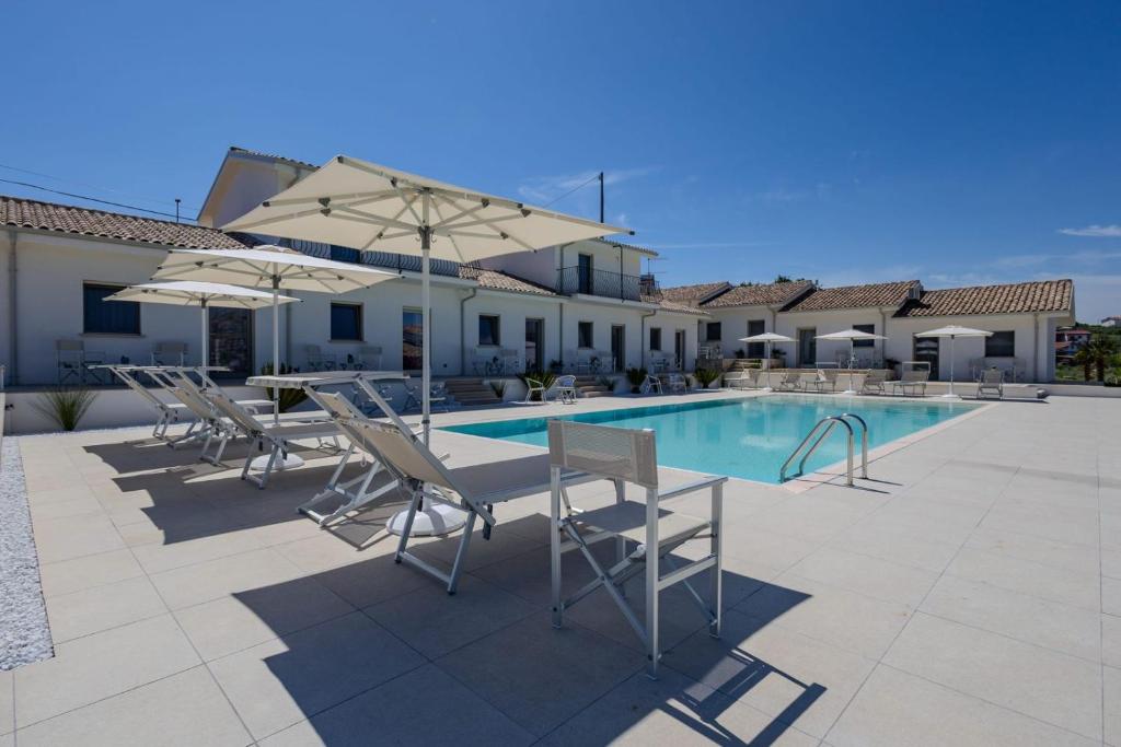 a pool with chairs and a table and umbrellas at Le Casette di Giò in Monteodorisio