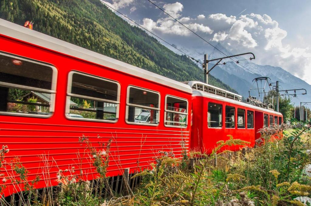 a red train is on the tracks in the mountains at Meilleur emplacement hypercentre avec parking privatif souterrain in Chamonix