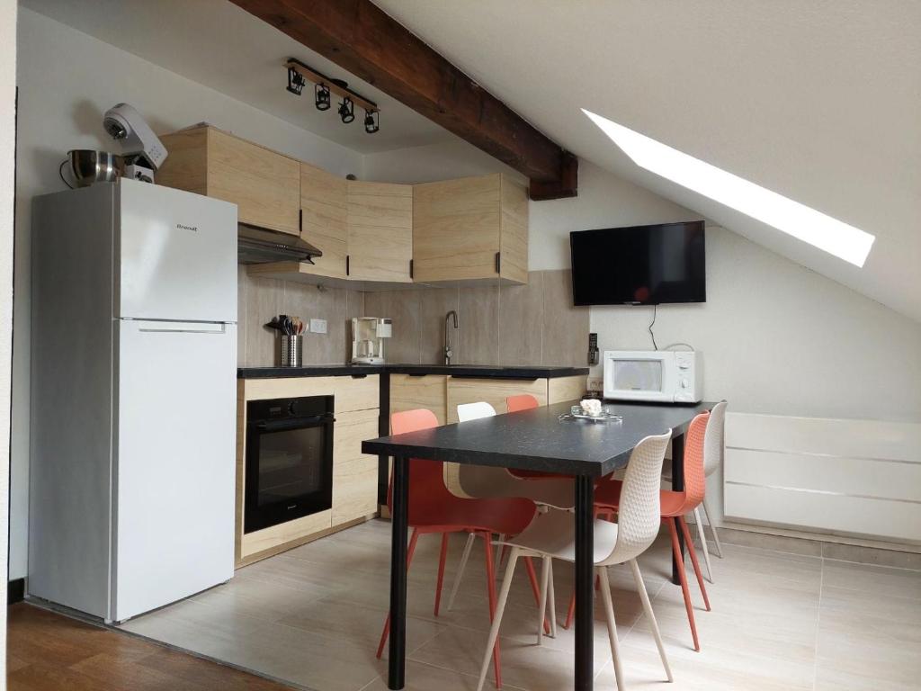 eine Küche mit einem schwarzen Tisch und einem weißen Kühlschrank in der Unterkunft Saint-Sorlin D'Arves 4-6 personnes pied des pistes 310km de pistes tous niveaux in Saint-Sorlin-dʼArves