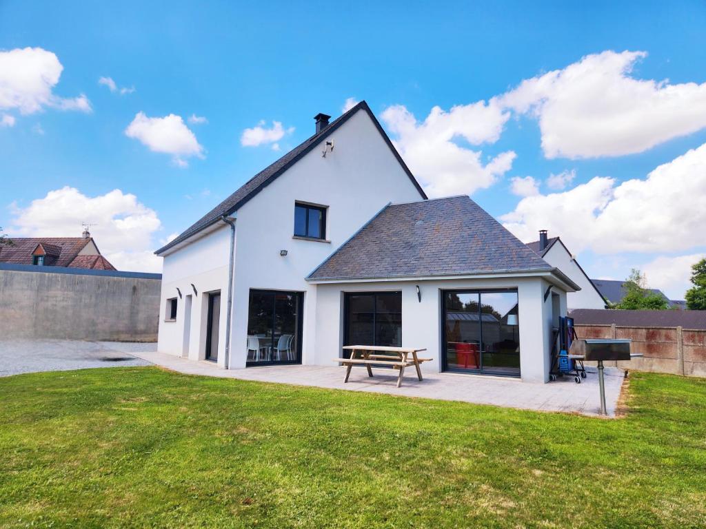 une maison blanche avec une table de pique-nique sur une pelouse dans l'établissement Maison spacieuse, à Moyon