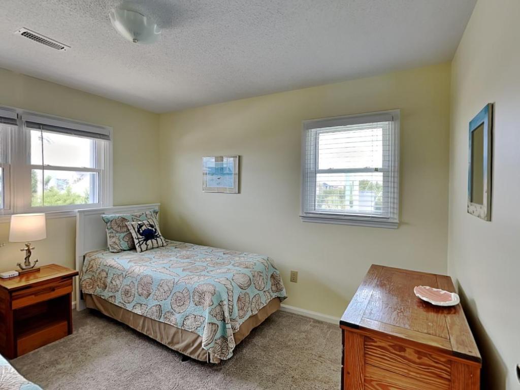 a bedroom with a bed and a desk and two windows at Happy Days in Surf City
