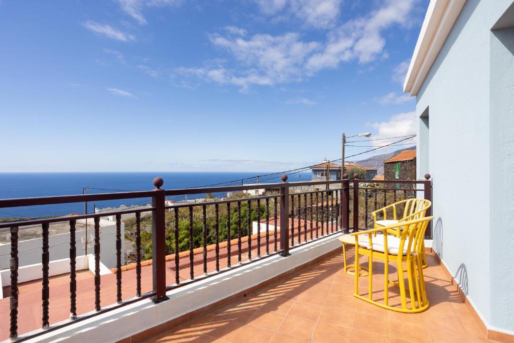 フロンテーラにあるHome2Book Casita del Lomo, Terrace & BBQの黄色い椅子付きのバルコニーから海の景色を望めます。