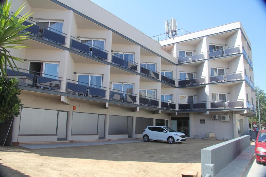 um edifício de apartamentos com um carro estacionado no parque de estacionamento em Aparthotel Els Molins em Roses
