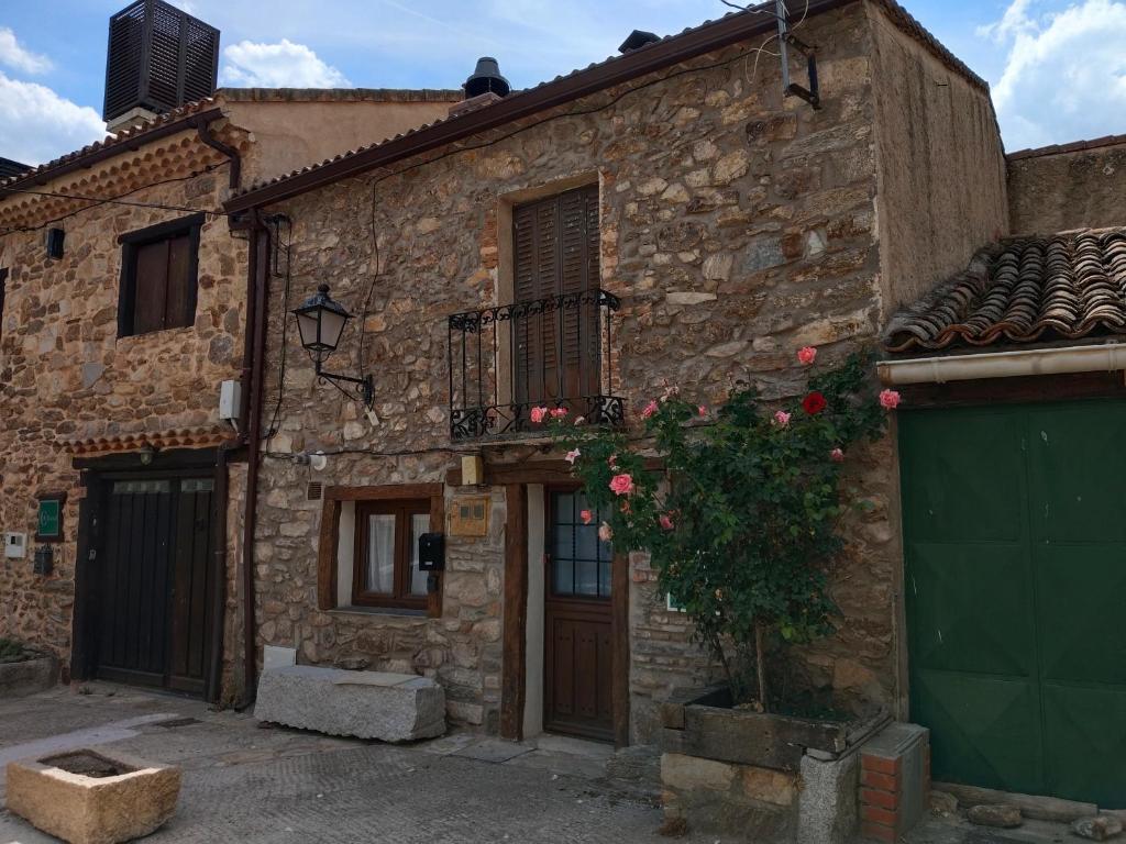 un antiguo edificio de piedra con puerta y balcón en Bellavieja, en Villavieja del Lozoya