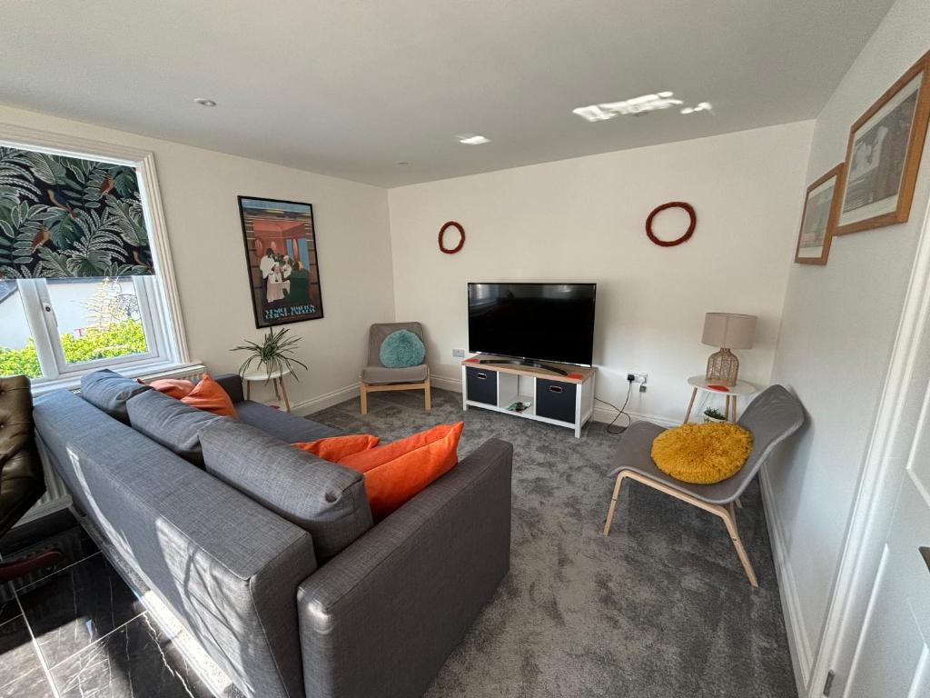 een woonkamer met een bank en een flatscreen-tv bij Holywell Apartments in Eastbourne